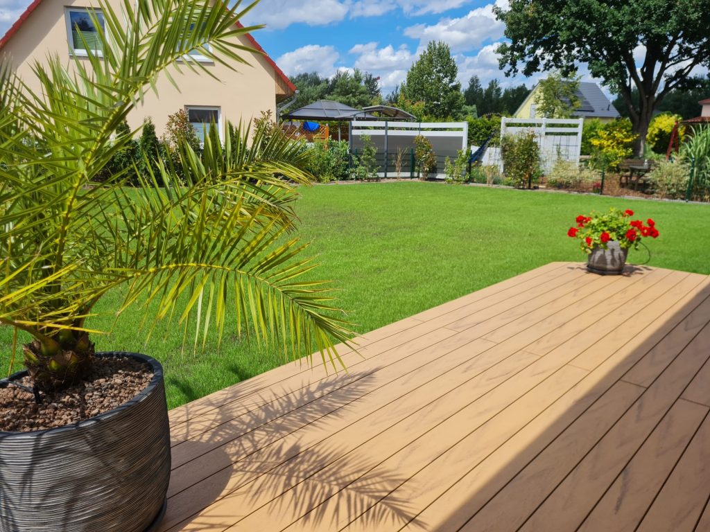 Holzterrasse mit Palme und Blick auf den Rasen – Garten- und Landschaftsbau in Teltow