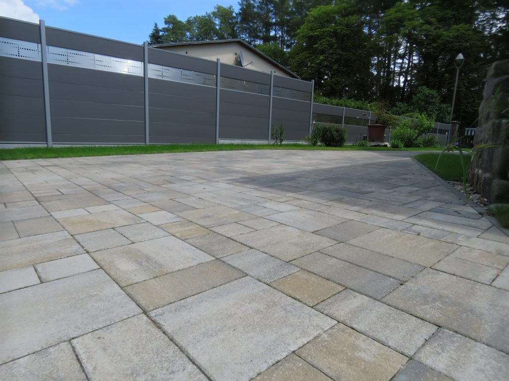 Großzügige Terrassenfläche aus Betonpflaster mit Sichtschutzzaun – Garten- und Landschaftsbau in Berlin