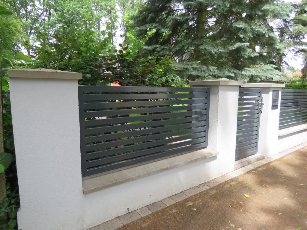 Moderner Metallzaun mit Tor zwischen weißen Mauerpfeilern
