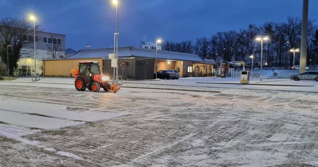 Winterdienst: Traktor mit Räumschild auf einem Parkplatz